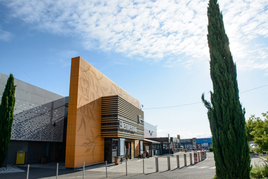 Ce centre commercial, situé à Orange, offre, en plus de son hypermarché carrefour,une variété de magasins et de restaurants pour tous les goûts. Les deux accès principaux sont vêtus d'un bardage orange perforé selon un plan précis afin d'en faire ressortir des formes de feuilles d'olivier.