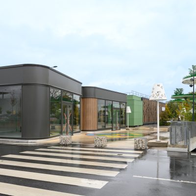 Situé à Pontault-Combault, ce centre commercial se veut moderne et écologique. Le bardage en stratifié haute pression sublime l'identité du site, avec une finition immitation bois et un découpage en forme de troncs d'arbres. Les parasols, eux aussi, rappellent la nature avec les découpes laser en forme de feuille. Un travail de précision pour un rendu de qualité.