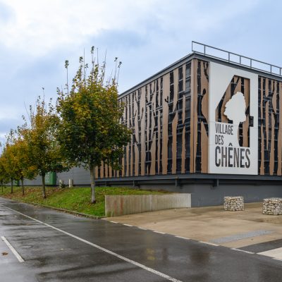 Situé à Pontault-Combault, ce centre commercial se veut moderne et écologique. Le bardage en stratifié haute pression sublime l'identité du site, avec une finition immitation bois et un découpage en forme de troncs d'arbres. Les parasols, eux aussi, rappellent la nature avec les découpes laser en forme de feuille. Un travail de précision pour un rendu de qualité.