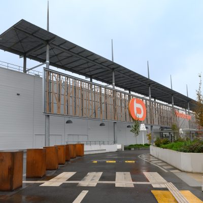 Situé à Pontault-Combault, ce centre commercial se veut moderne et écologique. Le bardage en stratifié haute pression sublime l'identité du site, avec une finition immitation bois et un découpage en forme de troncs d'arbres. Les parasols, eux aussi, rappellent la nature avec les découpes laser en forme de feuille. Un travail de précision pour un rendu de qualité.