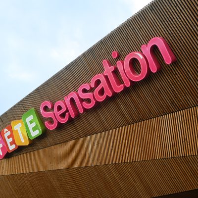 À Osny, ce centre commercial multi-enseignes est un centre de shopping, restauration et de loisirs. Parties vitrées, bardage en bois et en acier sont les éléments qui composent son habillage, montrant l'univers du possible, nottament avec le bardage en bois aux formes irrégulières.