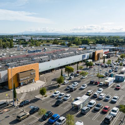 Ce centre commercial, situé à Orange, offre, en plus de son hypermarché carrefour,une variété de magasins et de restaurants pour tous les goûts. Les deux accès principaux sont vêtus d'un bardage orange perforé selon un plan précis afin d'en faire ressortir des formes de feuilles d'olivier.