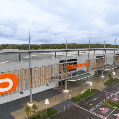 Situé à Pontault-Combault, ce centre commercial se veut moderne et écologique. Le bardage en stratifié haute pression sublime l'identité du site, avec une finition immitation bois et un découpage en forme de troncs d'arbres. Les parasols, eux aussi, rappellent la nature avec les découpes laser en forme de feuille. Un travail de précision pour un rendu de qualité.