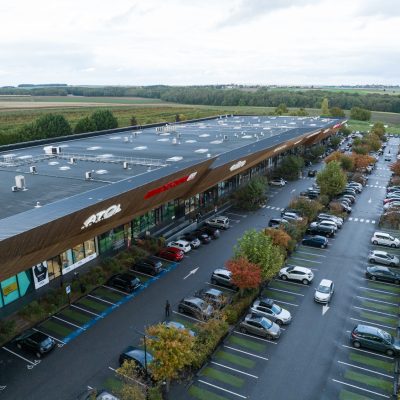 À Osny, ce centre commercial multi-enseignes est un centre de shopping, restauration et de loisirs. Parties vitrées, bardage en bois et en acier sont les éléments qui composent son habillage, montrant l'univers du possible, nottament avec le bardage en bois aux formes irrégulières.